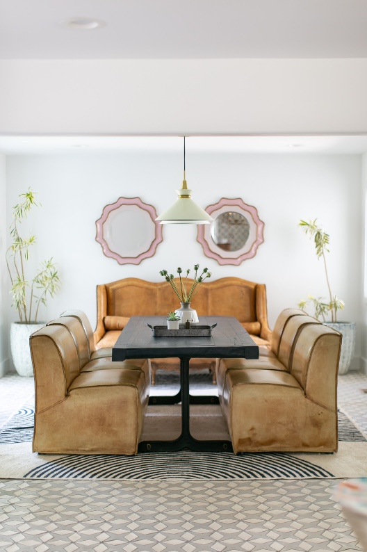 Dining room with cognac leather seating and scalloped blush mirrors