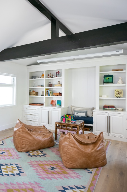 Family room with built-in shelving, leather poufs and colourful rug