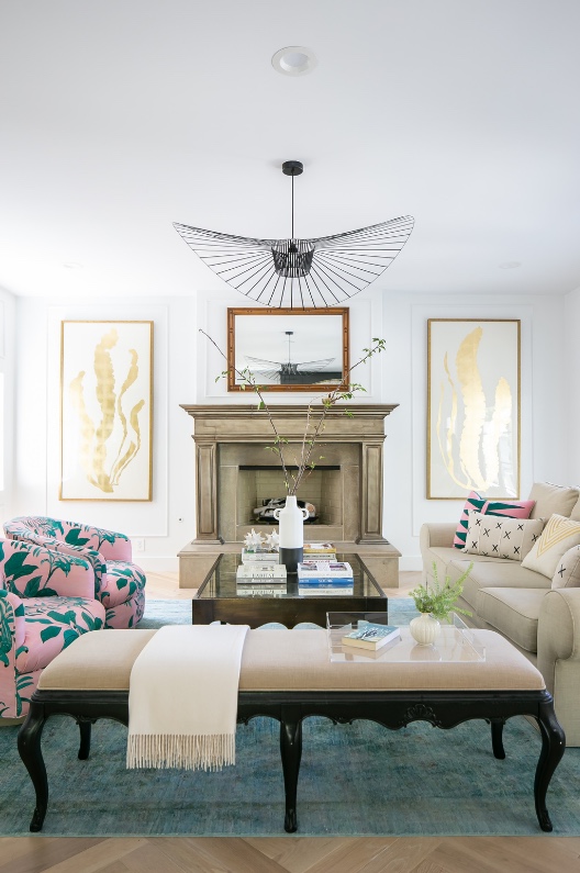 Living room with stone fireplace, tufted ottoman and feather pendant