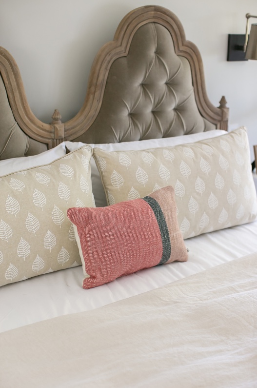 Bedroom with carved tufted headboard and block-print pillows