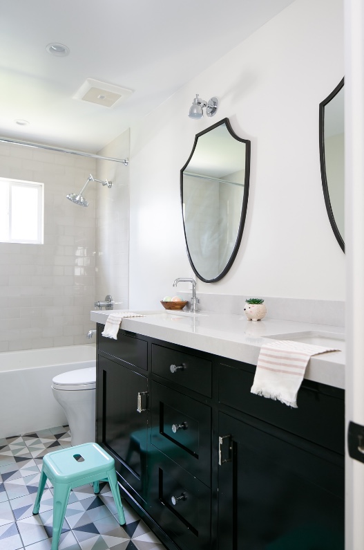 Bathroom with black vanity, shield mirror and teal stool