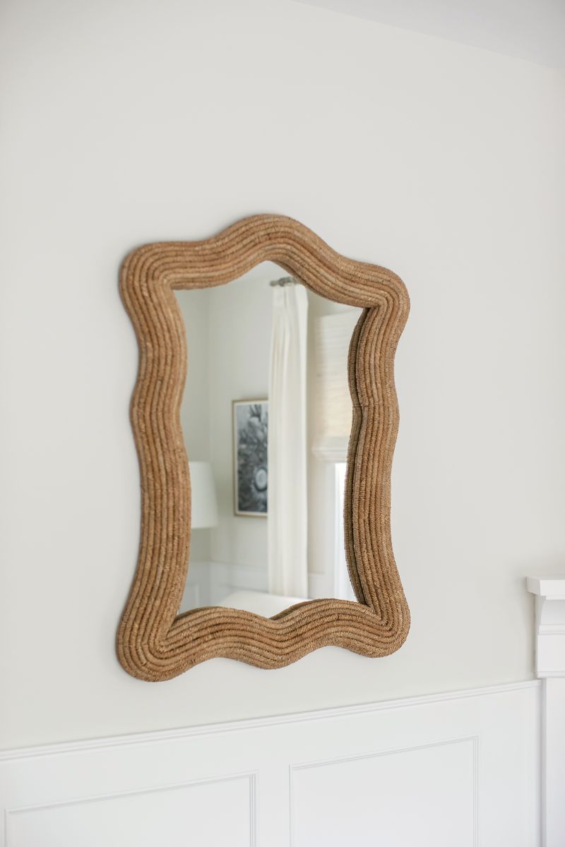 Rope-framed mirror above white wainscoting
