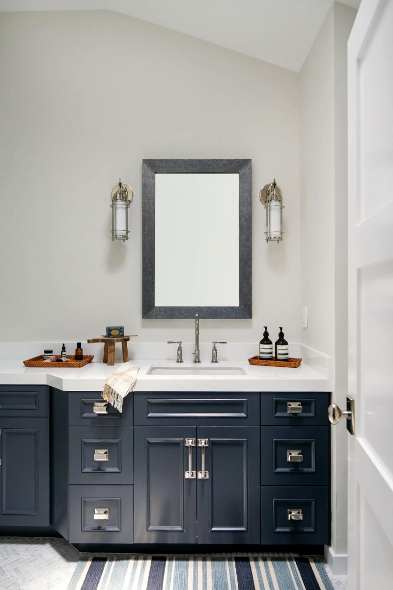 Powder room with navy vanity and brass sconces