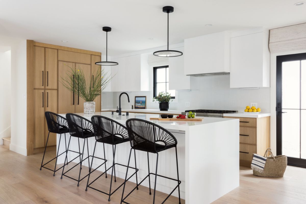 Kitchen with white oak cabinetry, white island and woven black counter stools