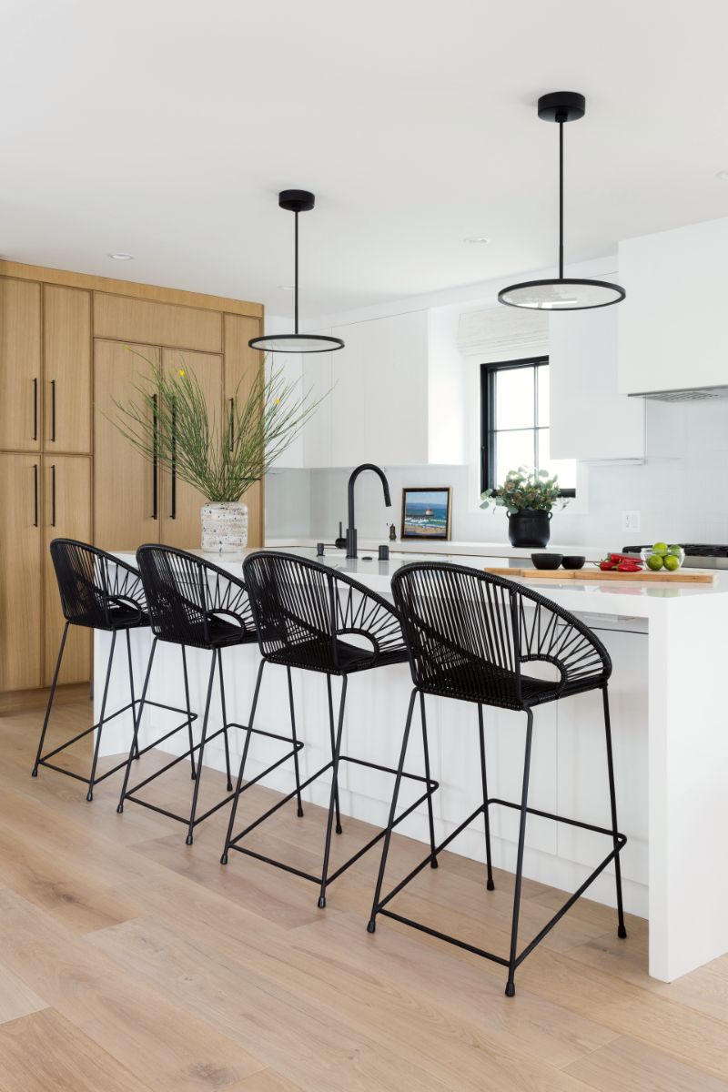 Kitchen island with woven counter stools and ring pendants