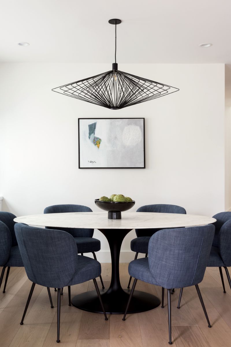 Dining table with navy velvet chairs under a sculptural wire pendant
