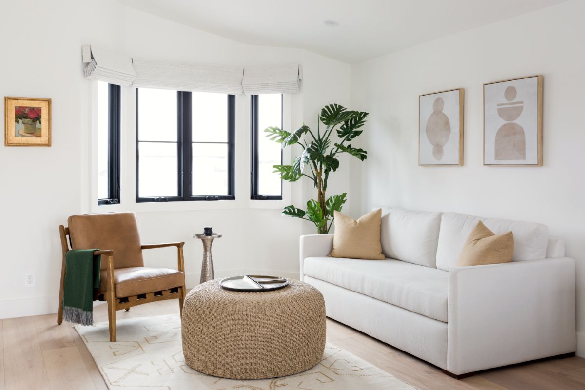 Sitting room with white sofa, leather chair and woven pouf