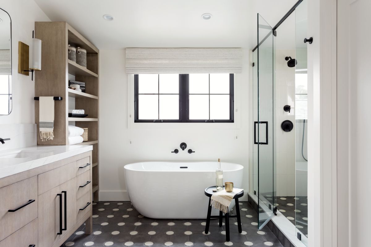 Bath with freestanding tub, oak vanity and black-and-white patterned tile