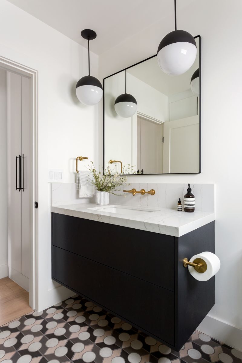 Powder room with black vanity, globe pendants and patterned tile