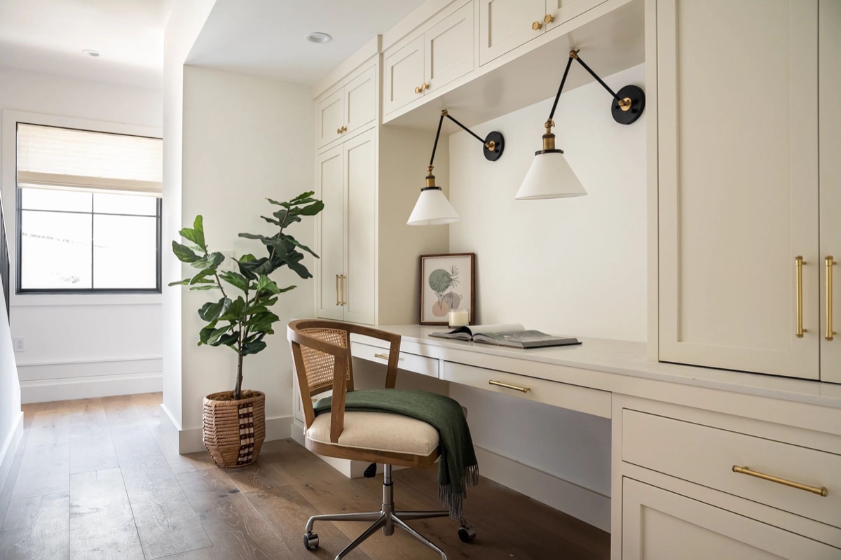 Built-in study nook with brass sconces and cane chair