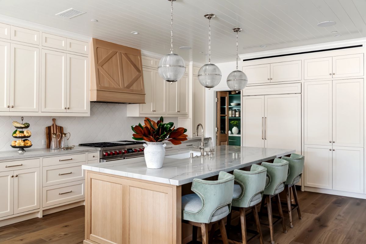 Kitchen with white oak island, marble counters, glass globe pendants and sage counter stools