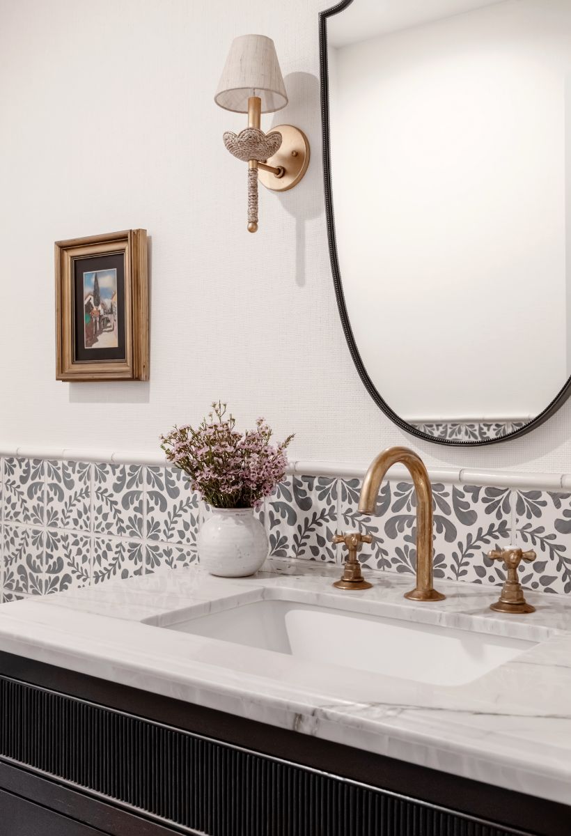 Powder room with patterned tile, fluted vanity and brass fittings
