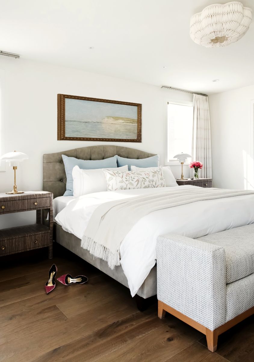Primary bedroom with upholstered headboard and landscape painting