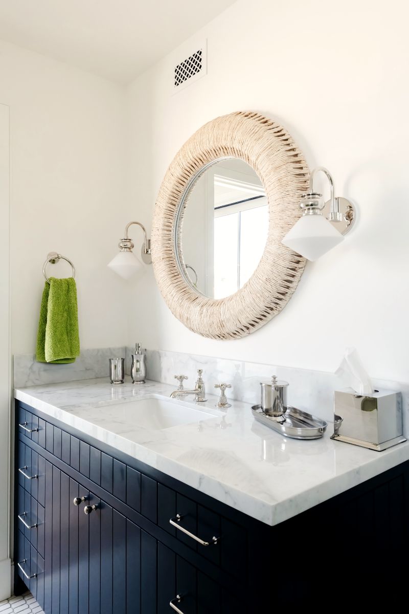 Guest bath with navy vanity and rattan mirror